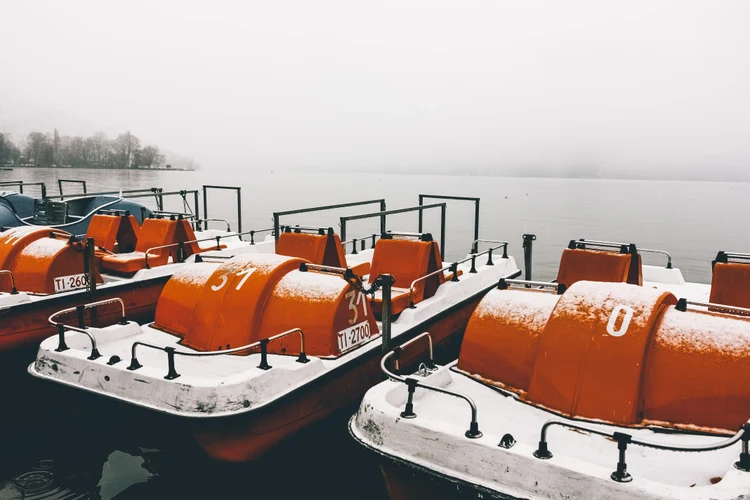 60a3d919-5c20-46e8-b5e1-f2c59f1c5997-orange-paddleboats-by-pier-calm-lake-captured-foggy-winter-day.jpg